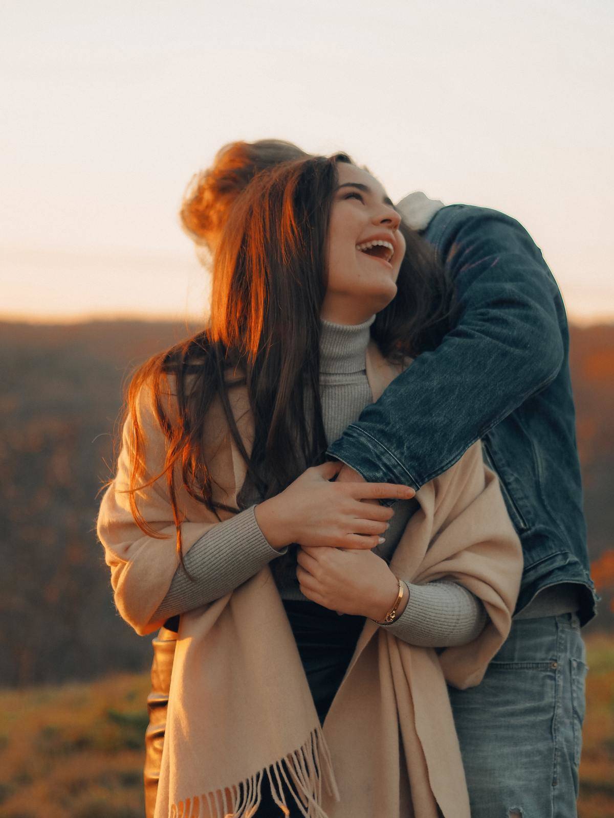Woman laughing alongside man with his arm wrapped around her