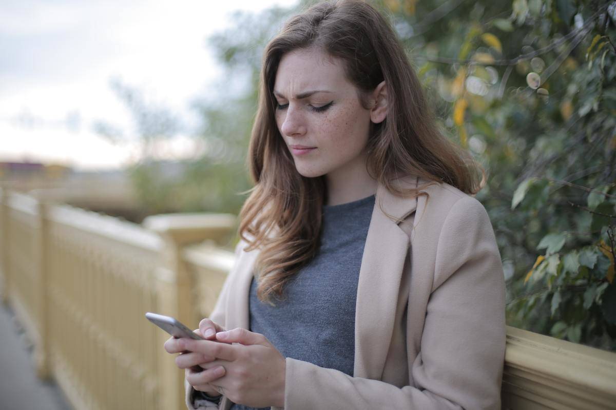 Woman looking confused at cellphone in her hands