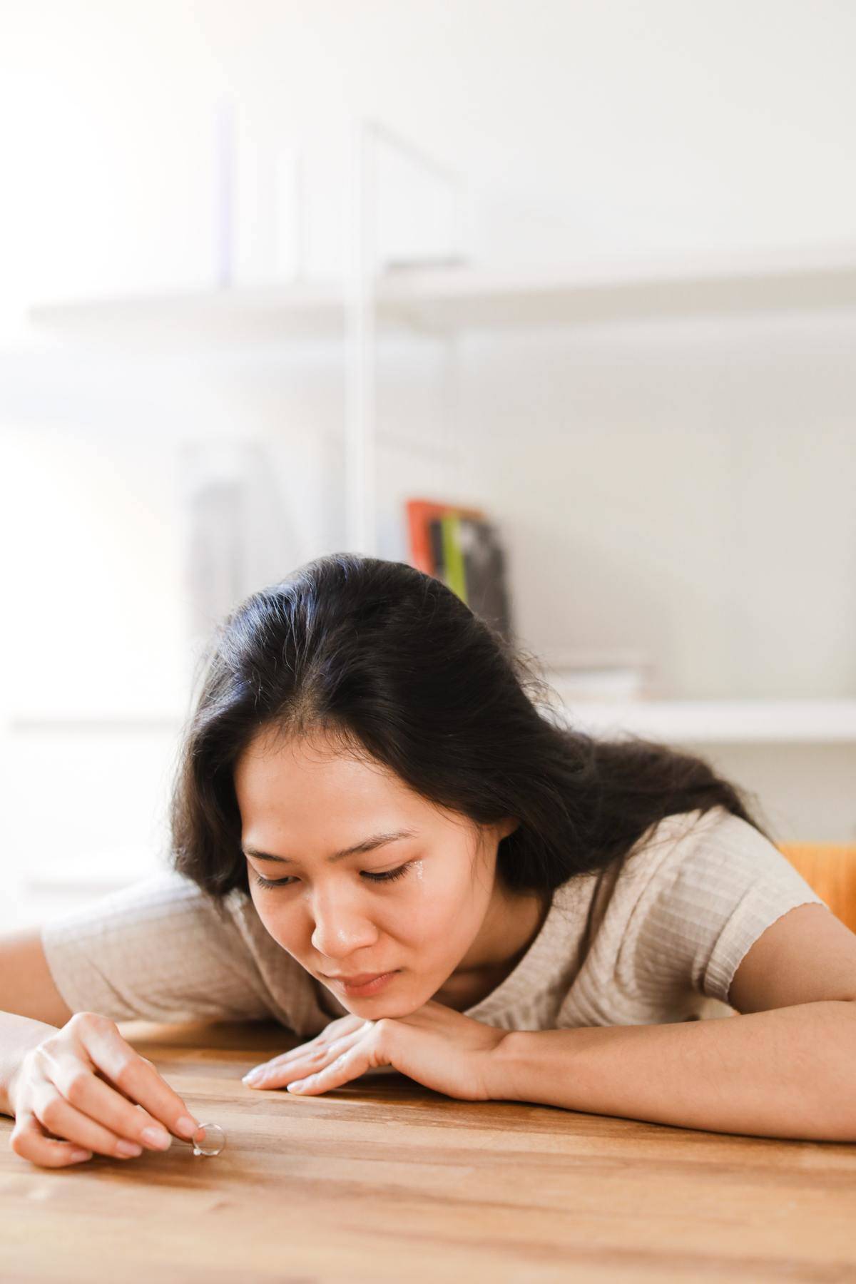Woman looking at ring in hand with head leaned on table