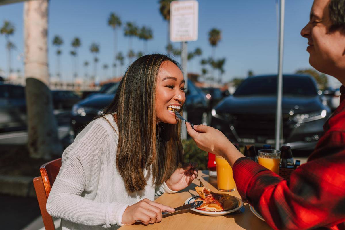 Woman laughing while eating off date's fork