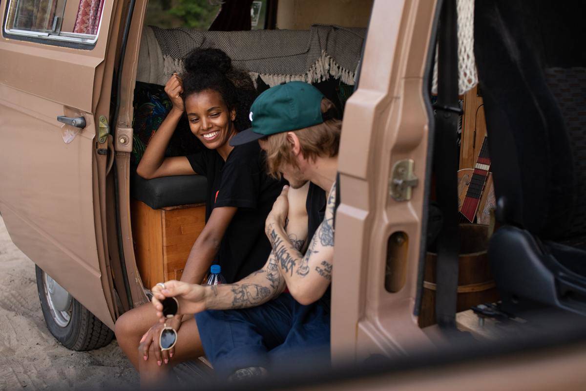 Couple sit in parked van out side doors talking