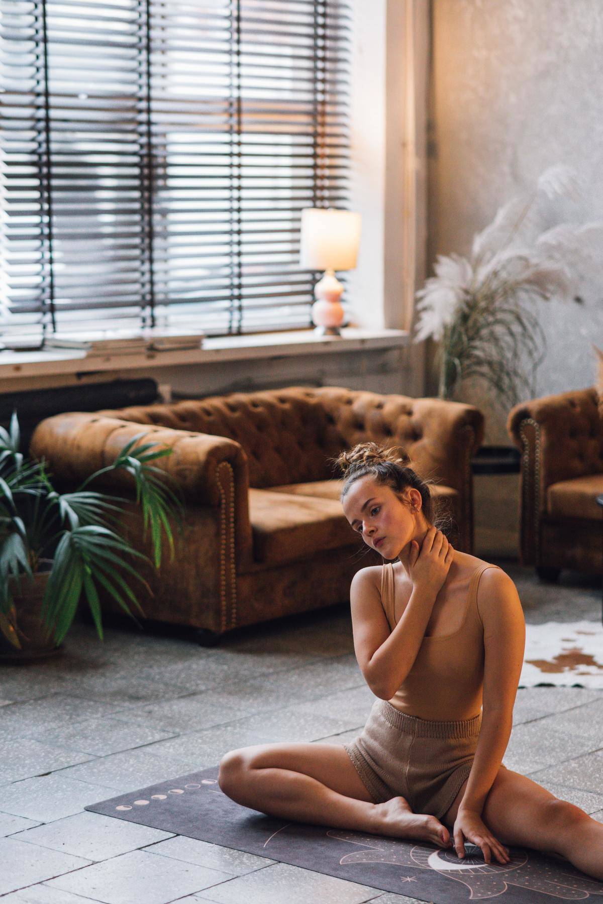 Woman doing yoga sitting on mat in living room