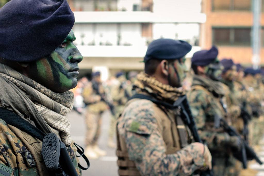Argentinian soldier in face paint and uniform lined outdoors, looking straight ahead