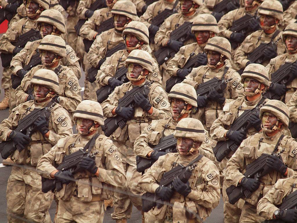 Peruvian army stand in uniform with guns against chest