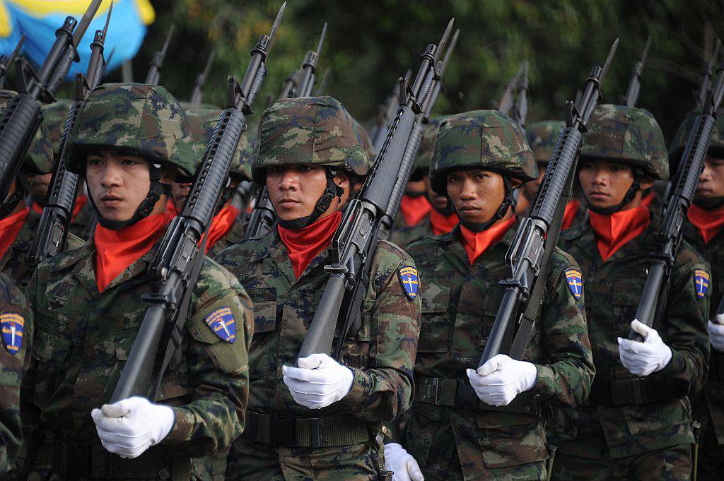 Thai soldiers stand at attention in military marching line with guns rested on soldiers