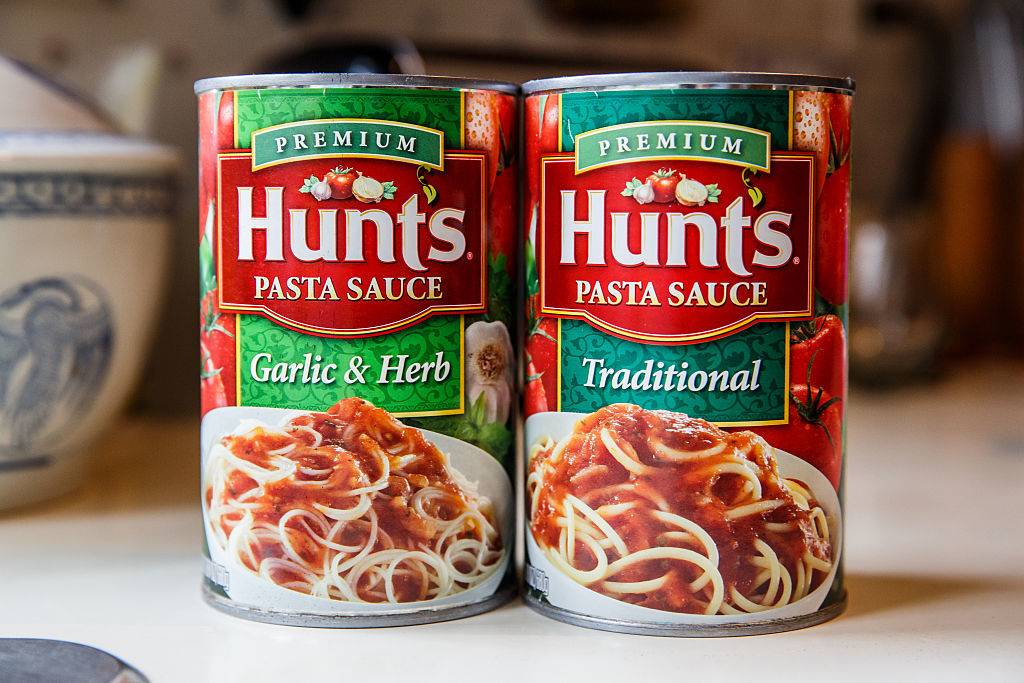 Two large cans of Hunt's brand premium Pasta Sauce in garlic and herb and traditional favors in the kitchen