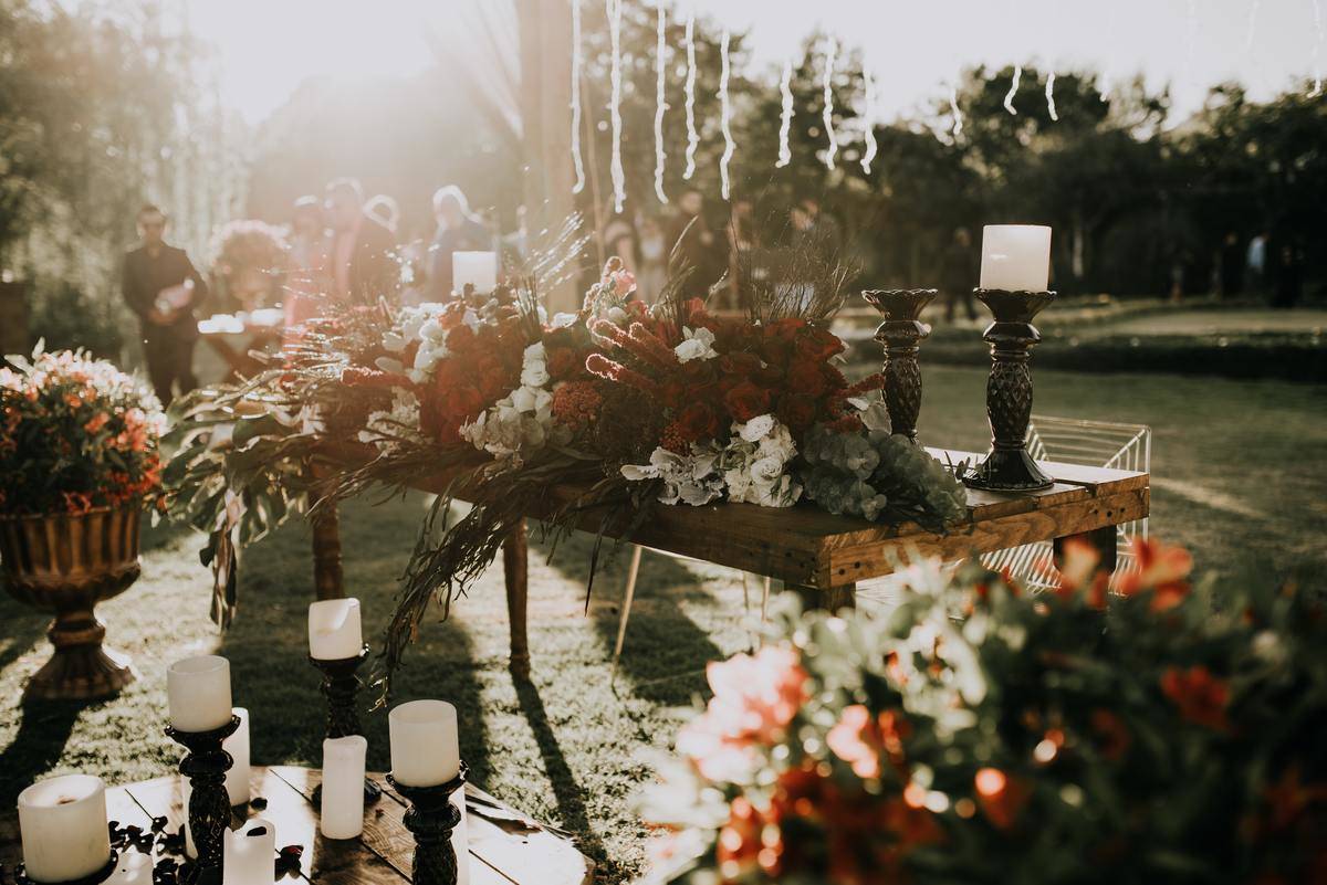 Photo of an outdoor wedding venue with large candelabra and flower vases on tables.