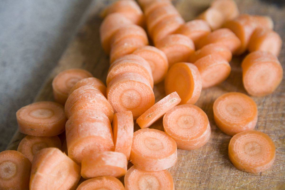 Sliced carrots on a wooden chopping board in a kitchen