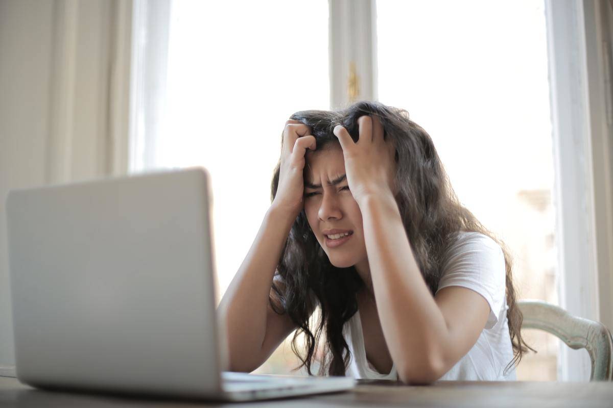 Woman frustrated holding hair looking at laptop screen