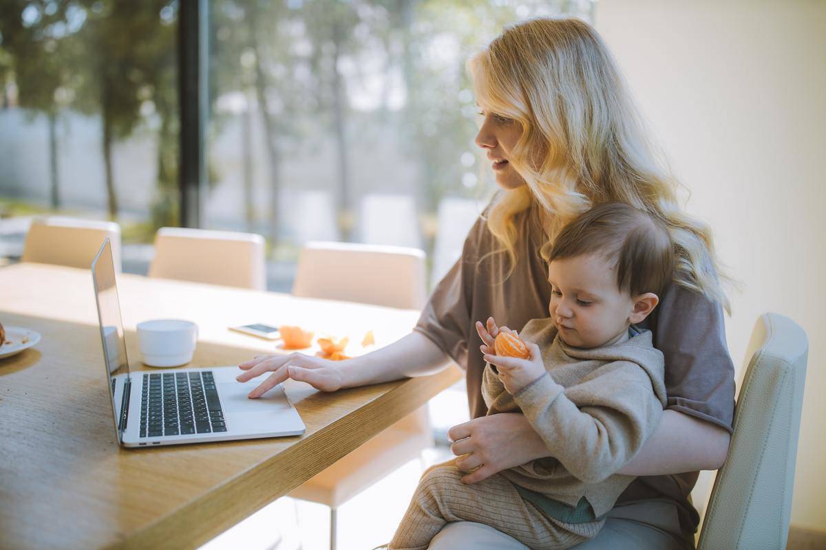 Woman sitting at laptop with baby on lap