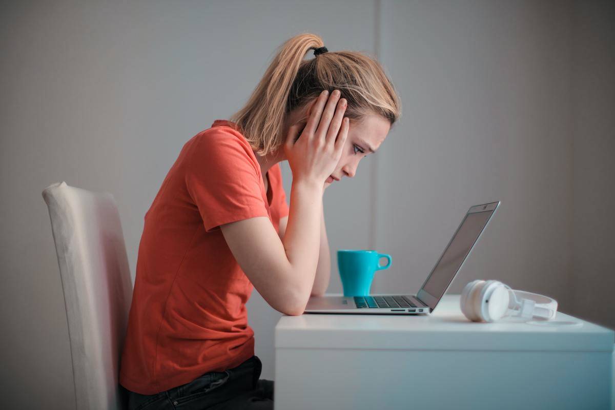 Woman looking frustrated with hands on head at laptop