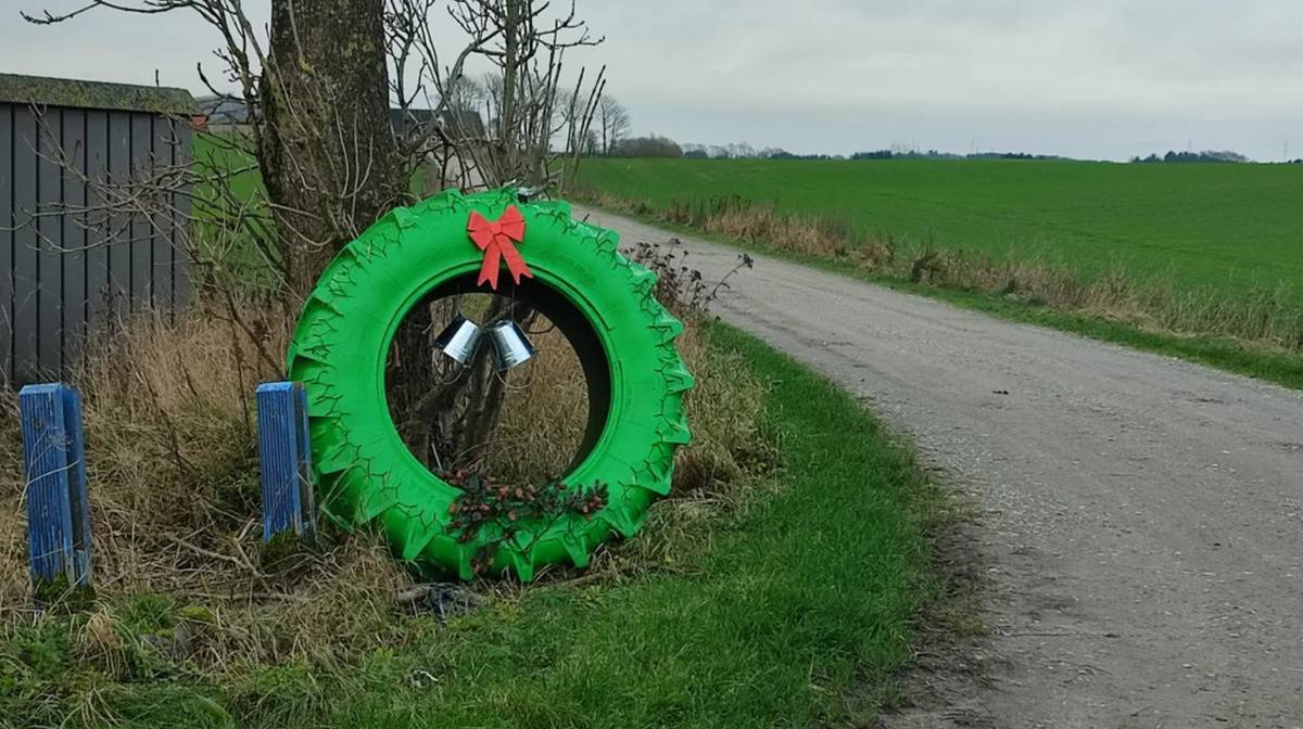 tractor tire painted green with red bow to look like wreath at the side of road