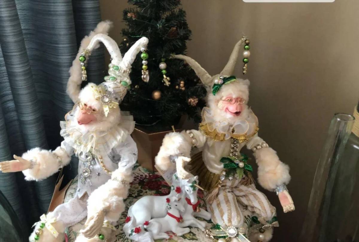 monkey dolls dressed like Victorian clowns next to unicorn figurines and in front of small Christmas tree