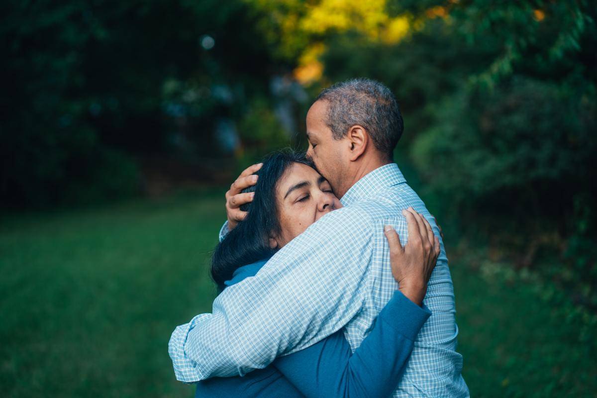 Man and woman hugging in clearing next to trees