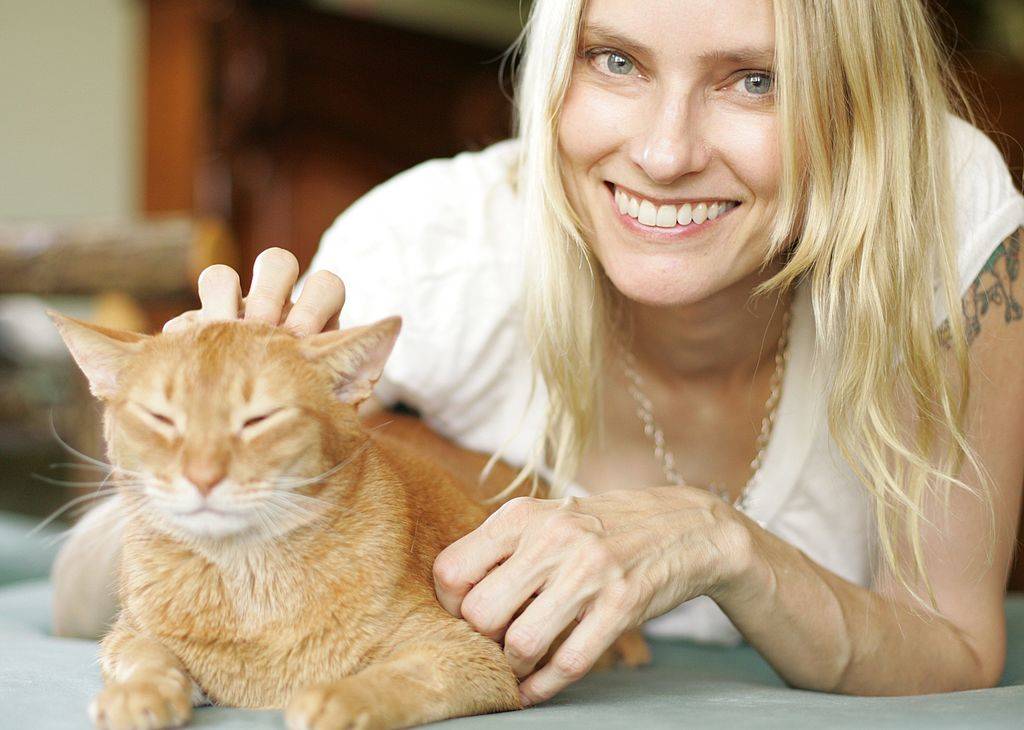 a cat being pet by a blonde woman