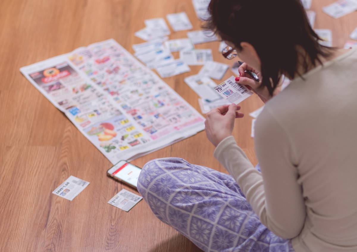woman-at-home-clipping-coupons-from-news-paper-on-2022-11-15-06-43-03-utc