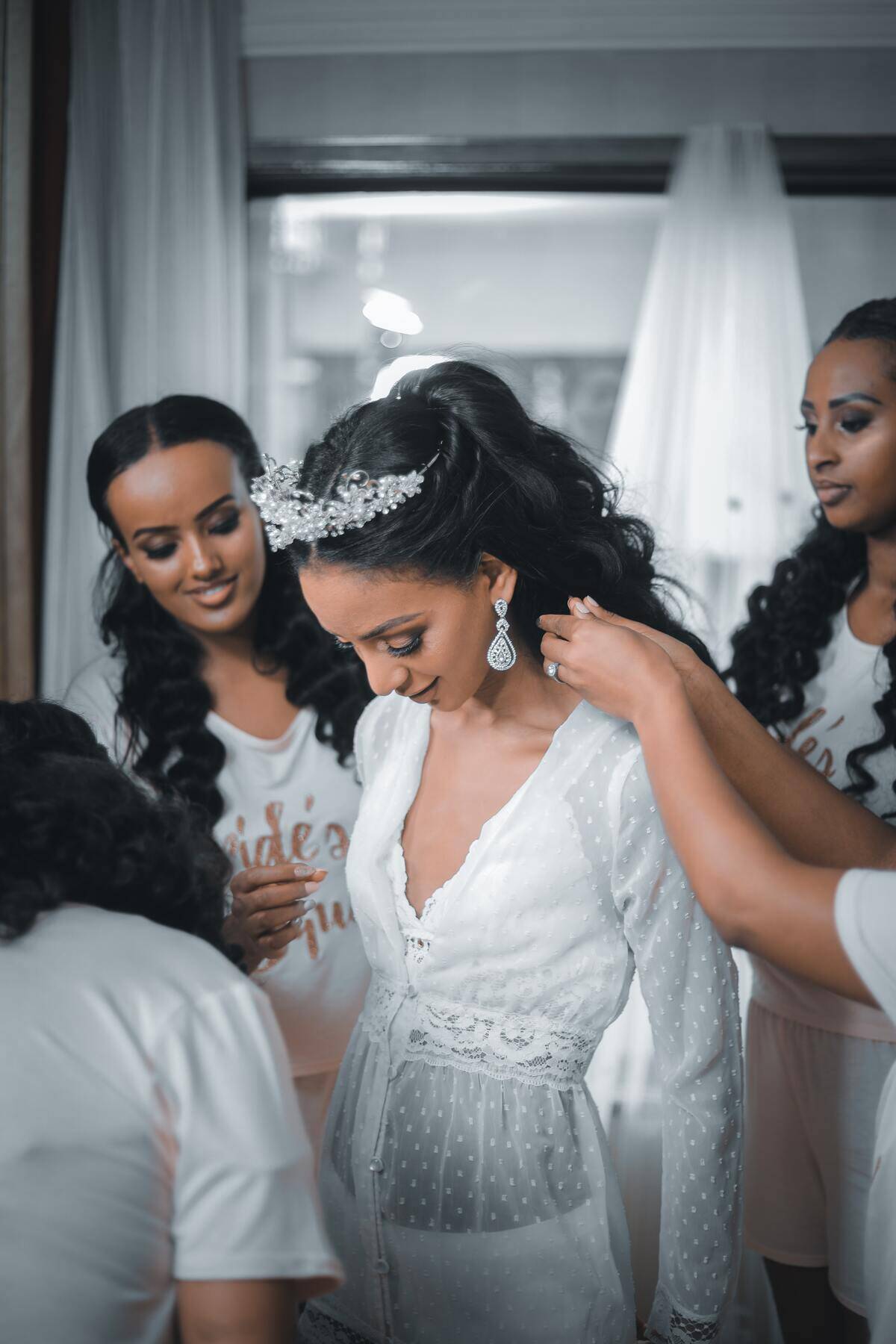 bridesmaids primping bride's hair as she looks down