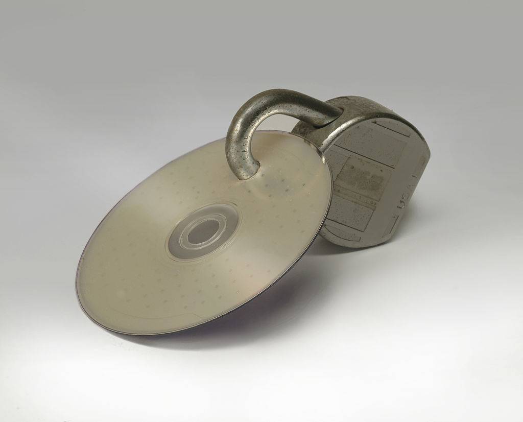 Close-up view of compact disc attached to a padlock through a hole drilled into its surface