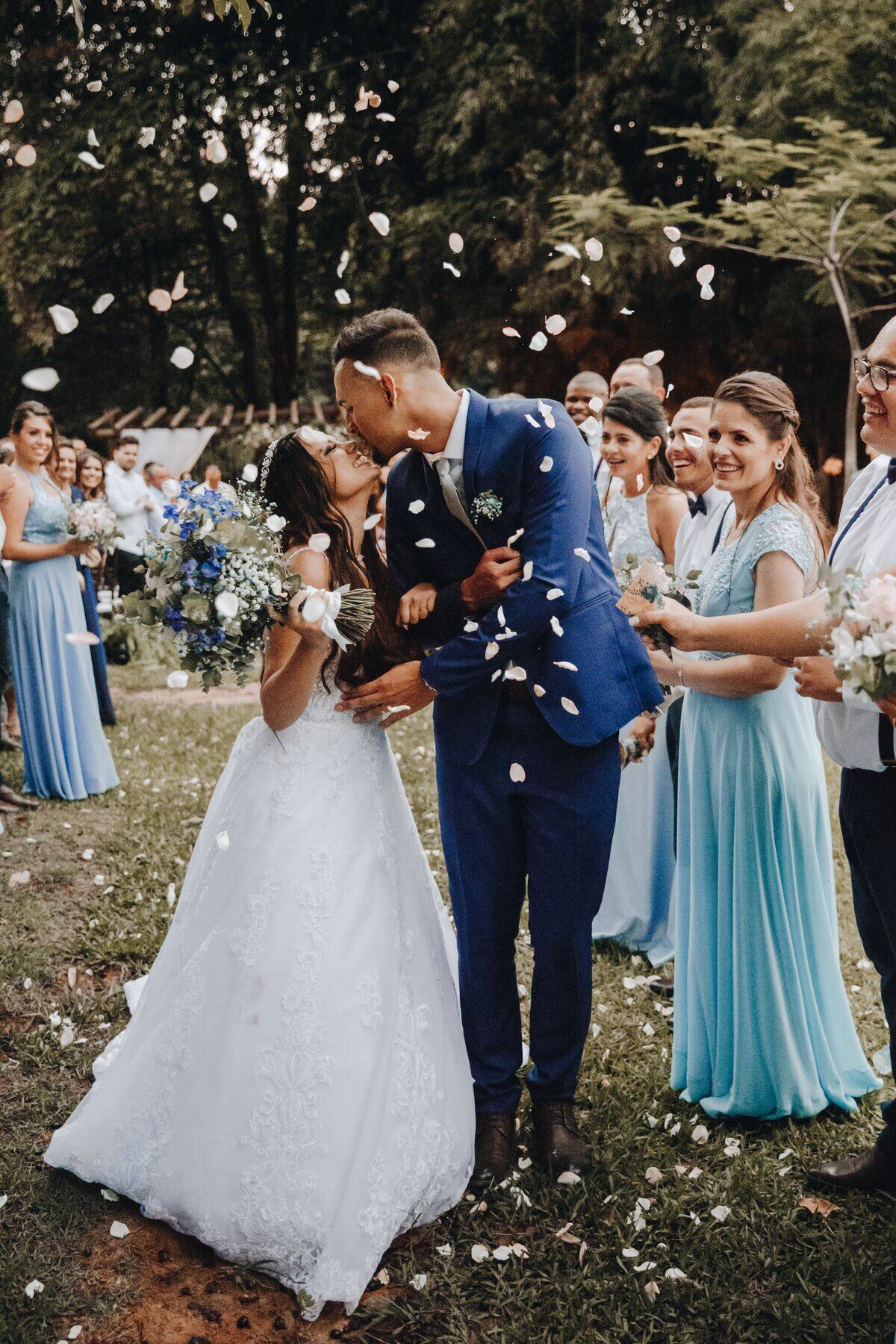 newly wedded couple holding each other close while guests cheer and throw confetti