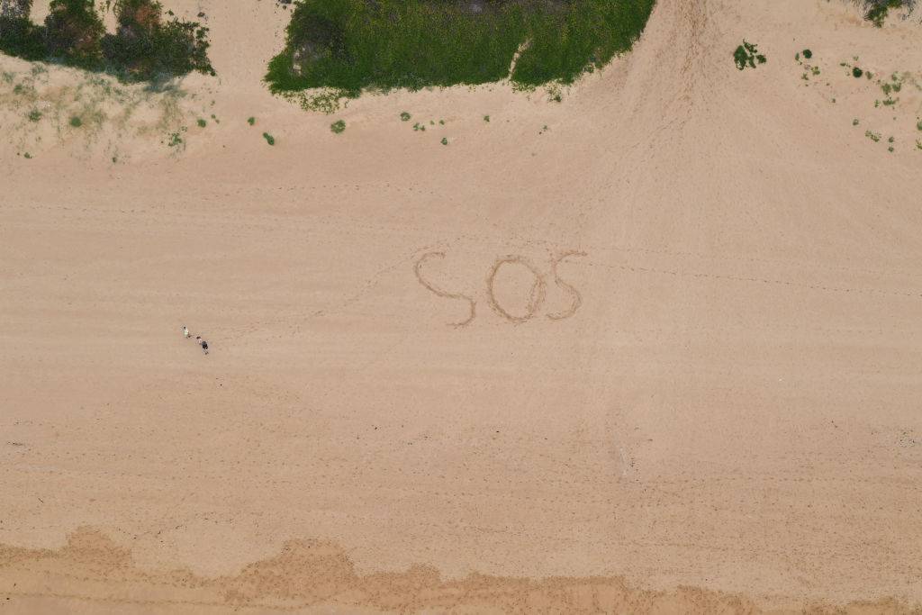 An aerial view of 'SOS' written in the sand