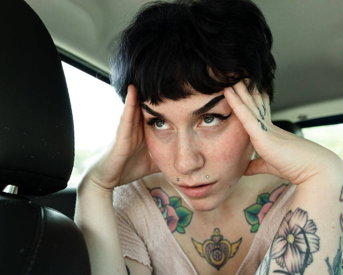 stressed woman touching her head in car's back seat