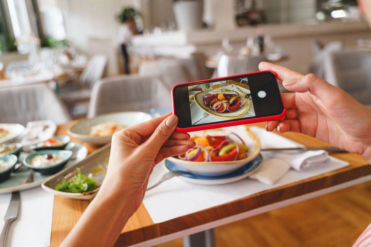 woman's hands grip phone as she takes photo of her lunch