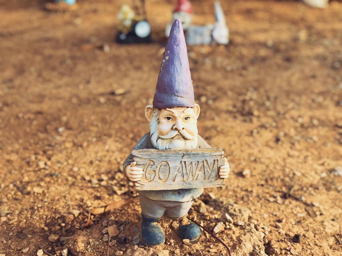 garden gnome holding sign saying 'go away'