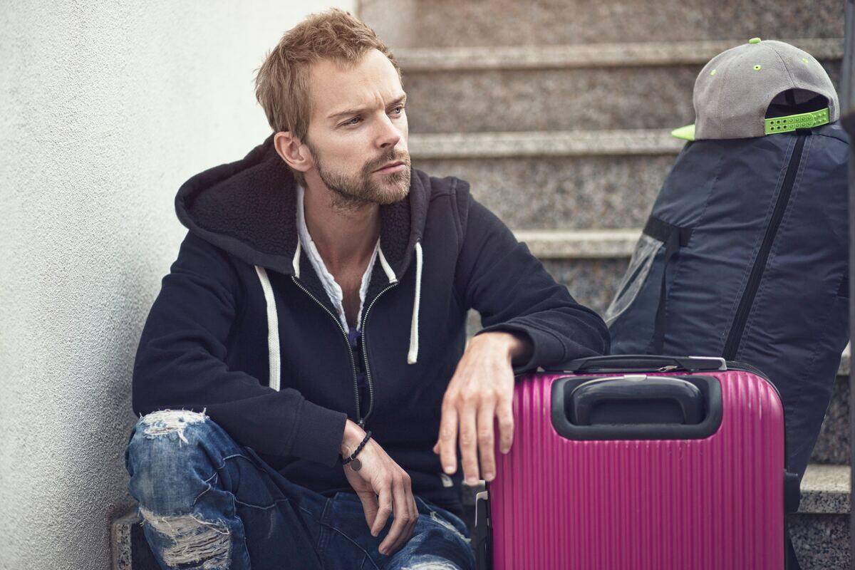 man angrily sitting on steps next to suitcases