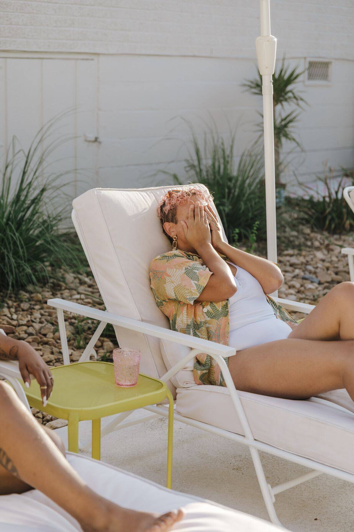 woman in pool chair covering her face with her hands