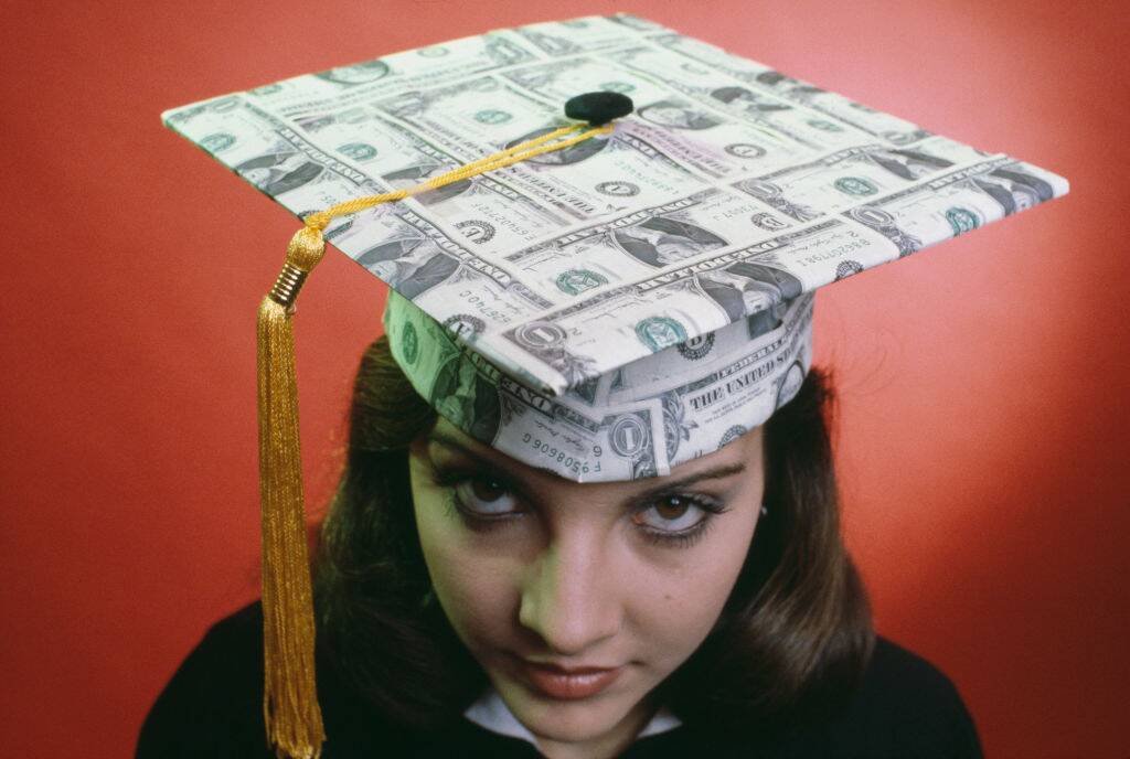 A female student wearing a square academic hat made of one-dollar banknotes