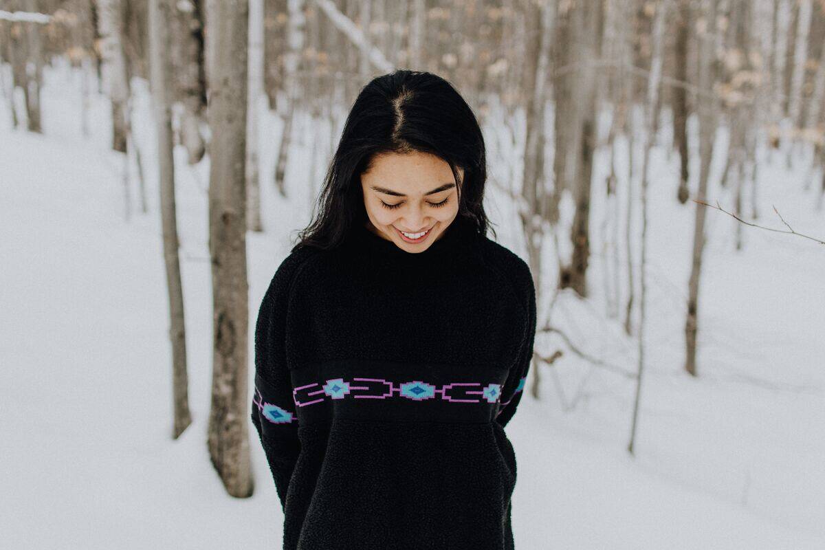 woman looking down bashfully amid winter forest