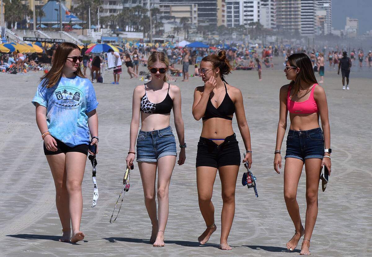 People enjoy themselves while walking along the beach. As...
