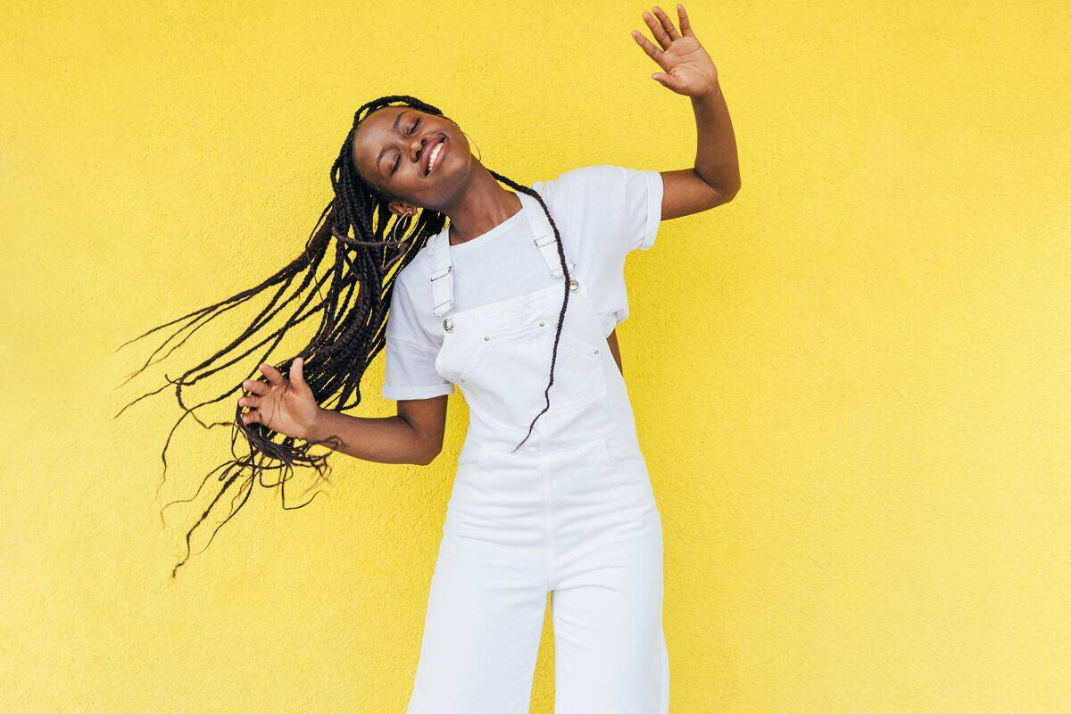 girl in white outfit dancing in front of yellow wall