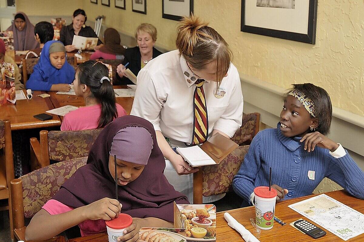 Cintia Ntanda, 11, gives her order to waitress Mistey Charrier, as her friend, Ayan Mohamed, 12, lef