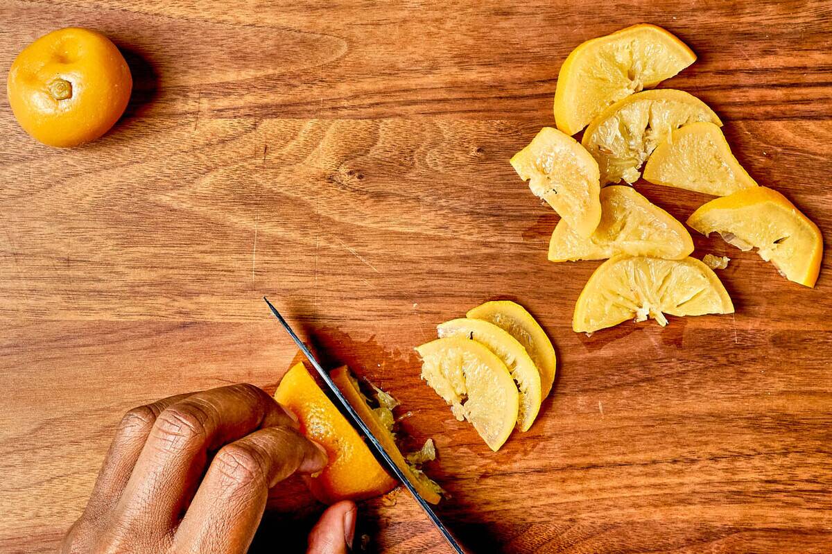 Slicing preserved lemon on the cutting board.Skillet Chicken Thighs With Preserved Lemon and Orzo for Dinner in Minutes column in Food