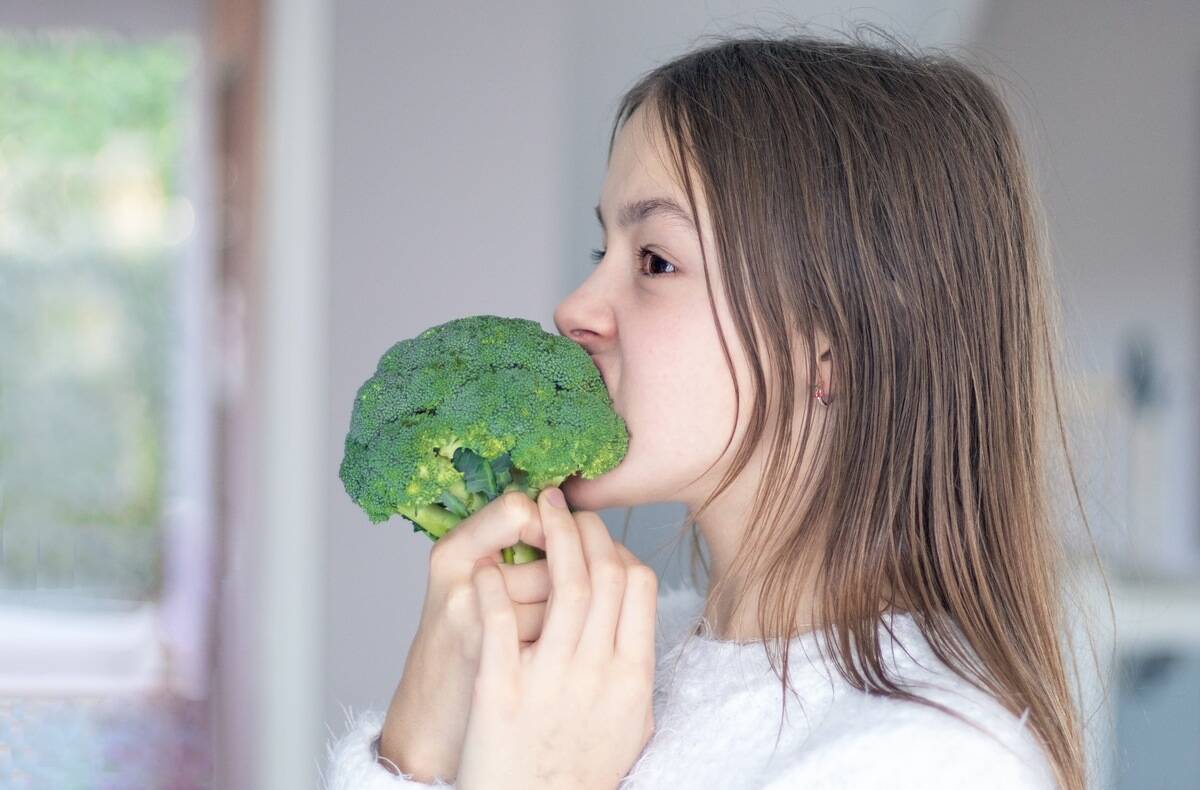 funny-preteen-girl-biting-and-eating-raw-broccoli-2025-02-12-00-45-27-utc