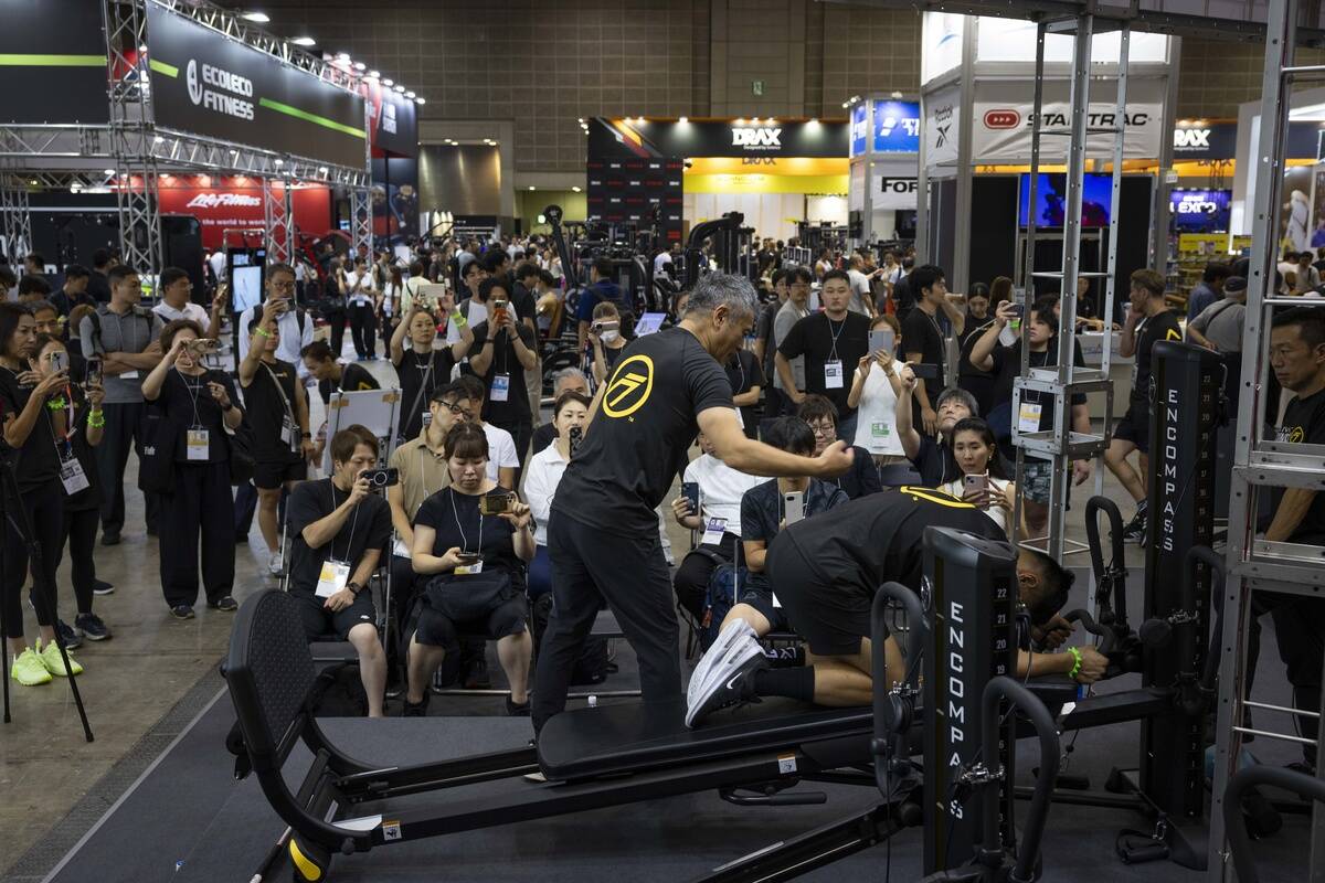 A fitness instructor demonstrates an exercise with his...