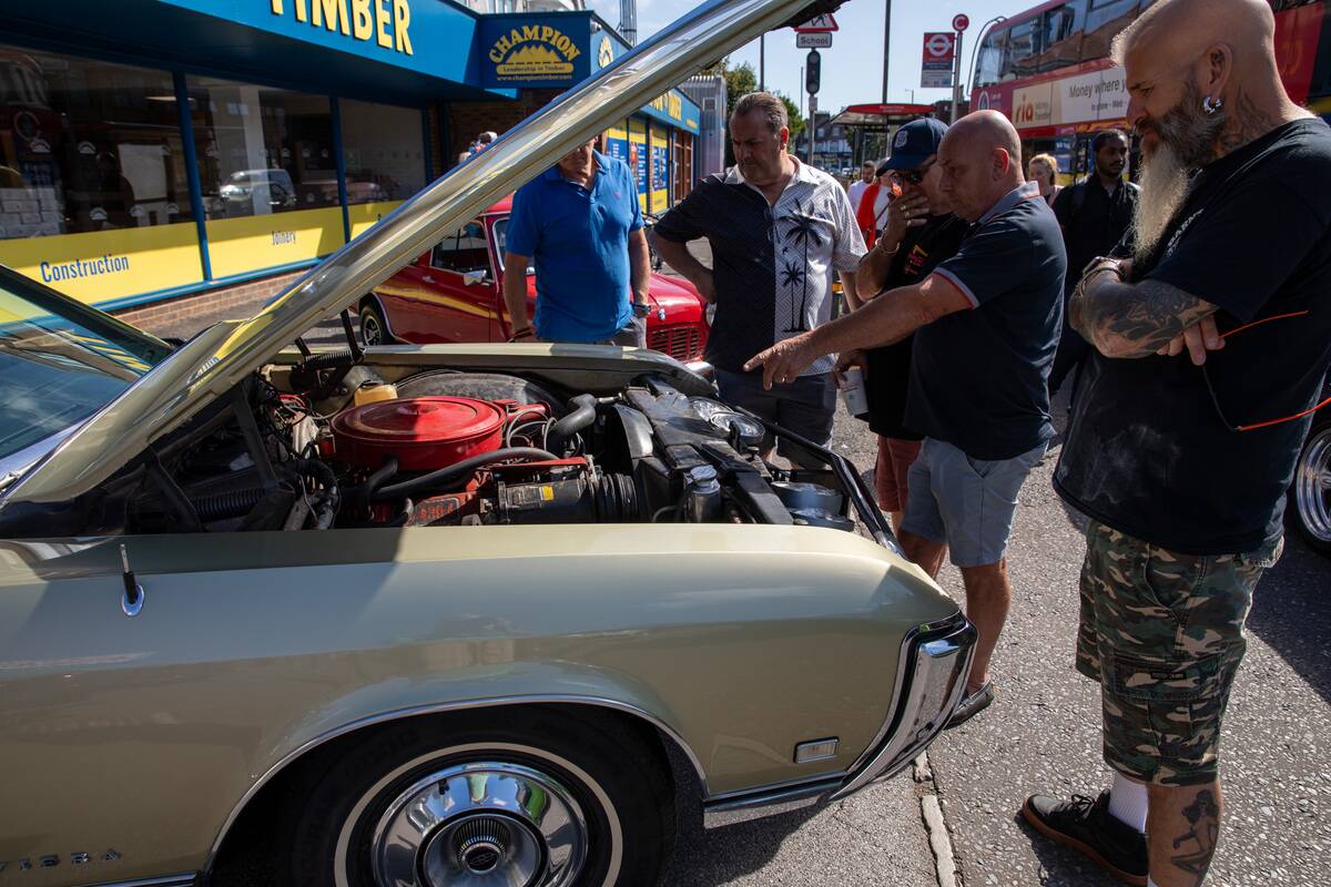 A group of men inspects the engine of a 1968 Buick Riviera...