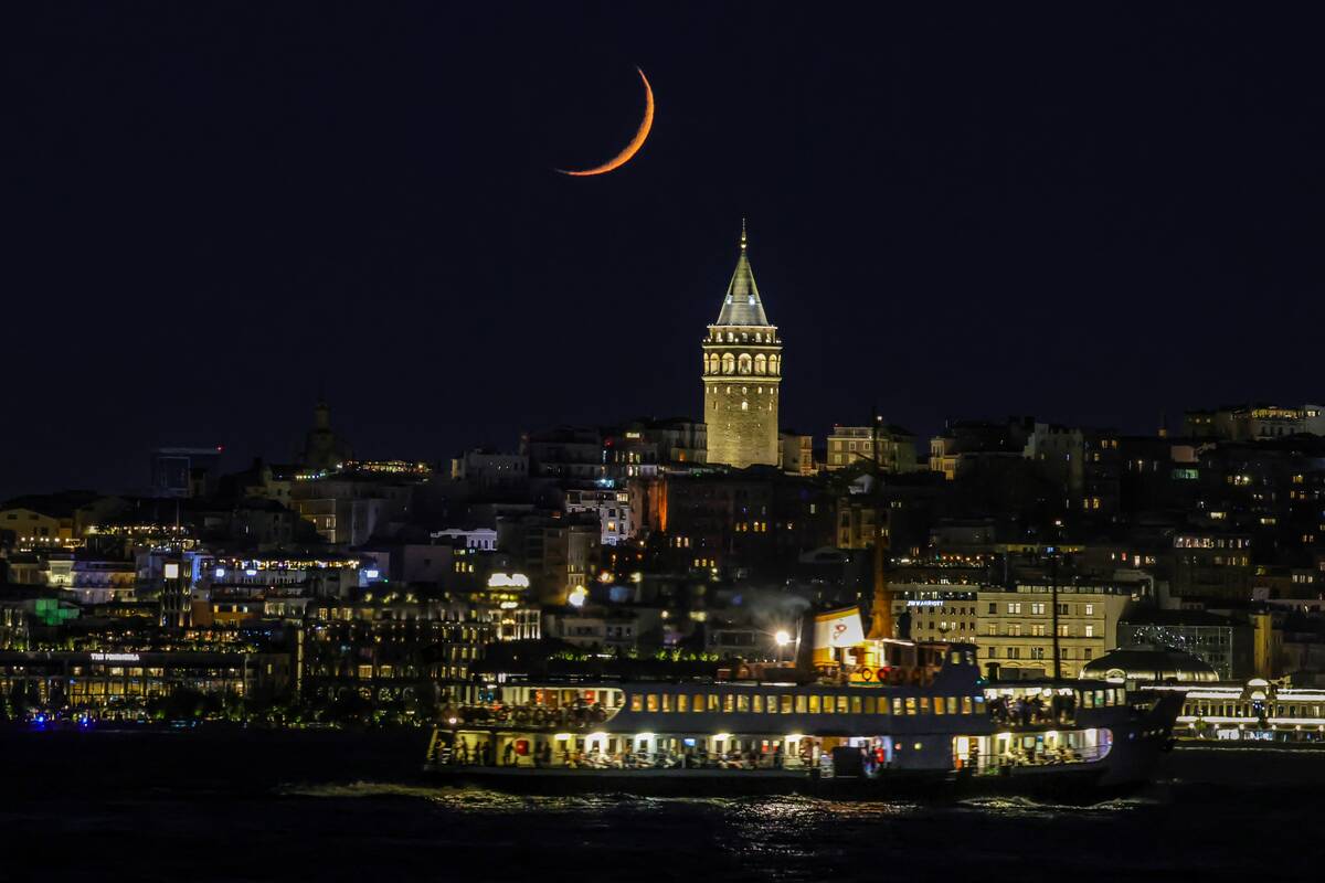 Crescent moon aligns with Galata Tower in Istanbul's night sky