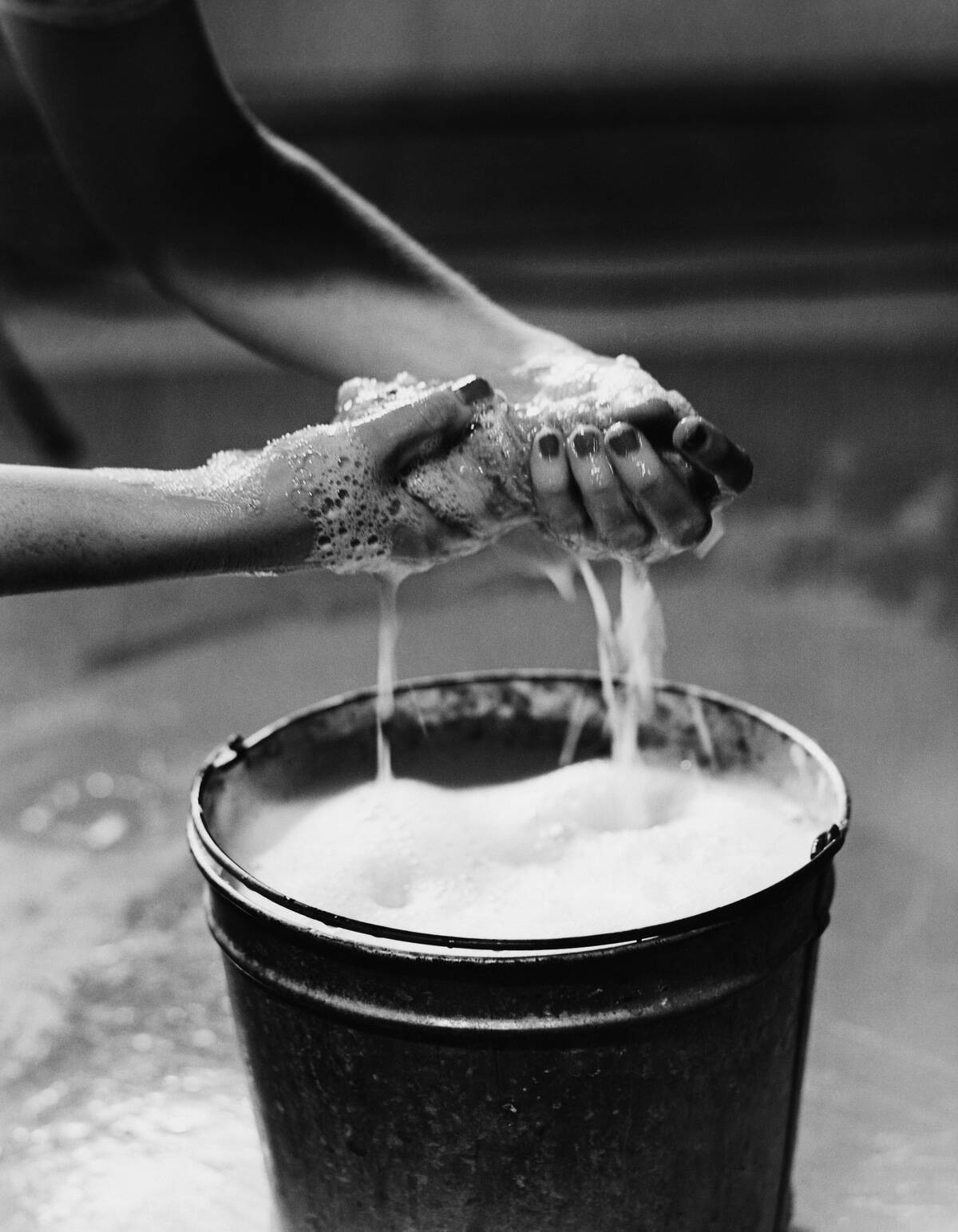 WOMAN WRINGING SOAP FROM SPONGE, CLOSE-UP