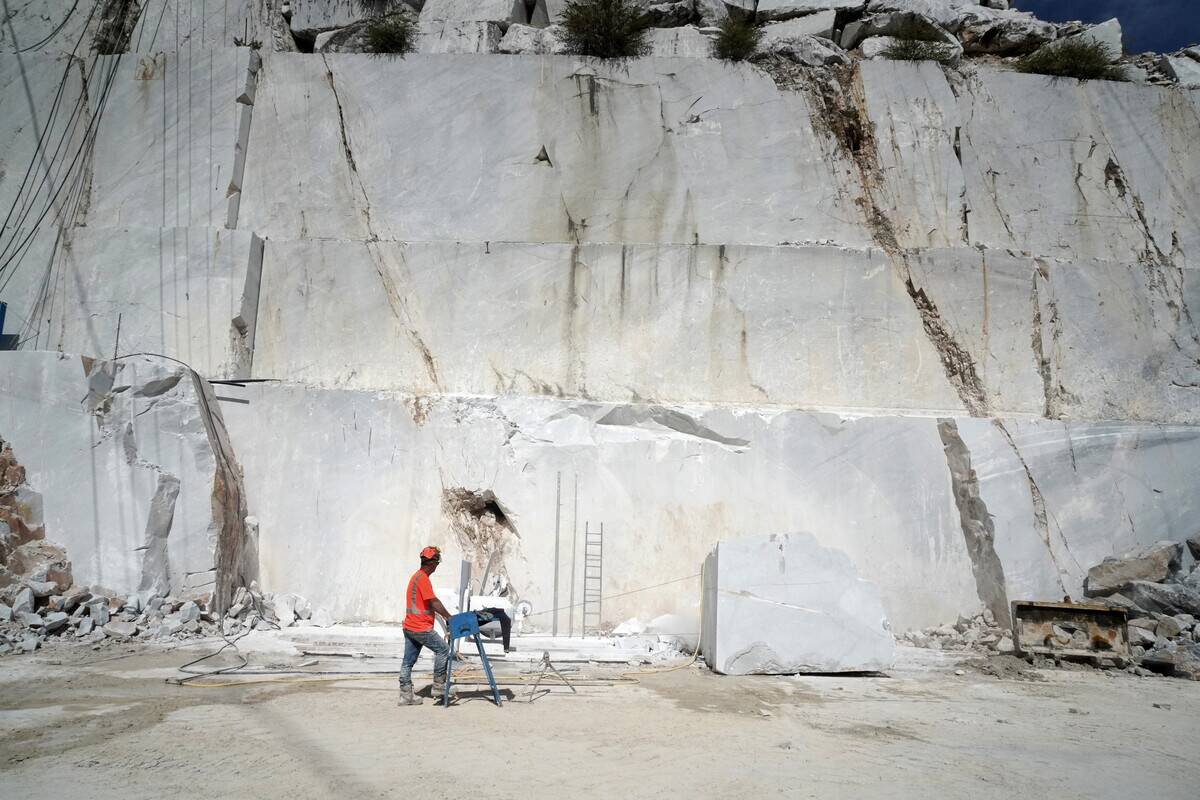 A worker at work in a section of a marble quarry. Carrara...