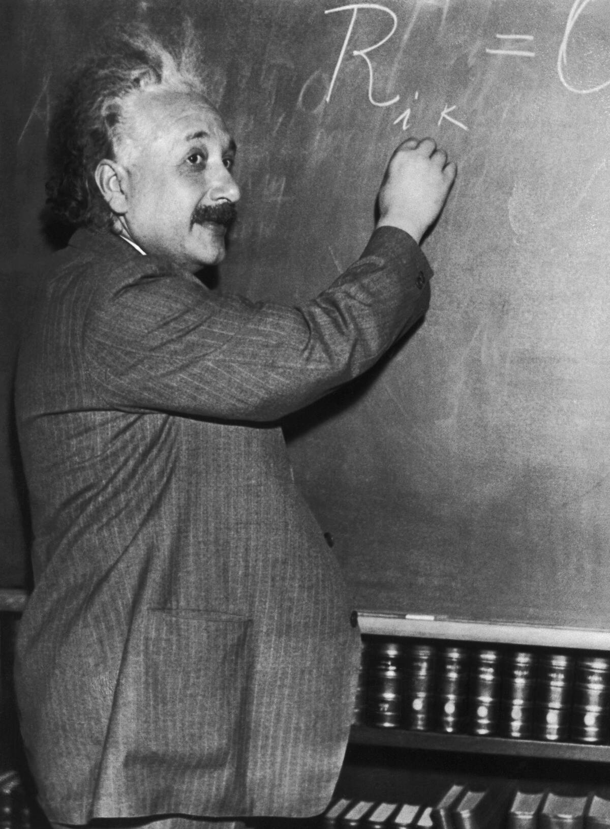 Albert Einstein Writing Mathematic Formulas on Blackboard