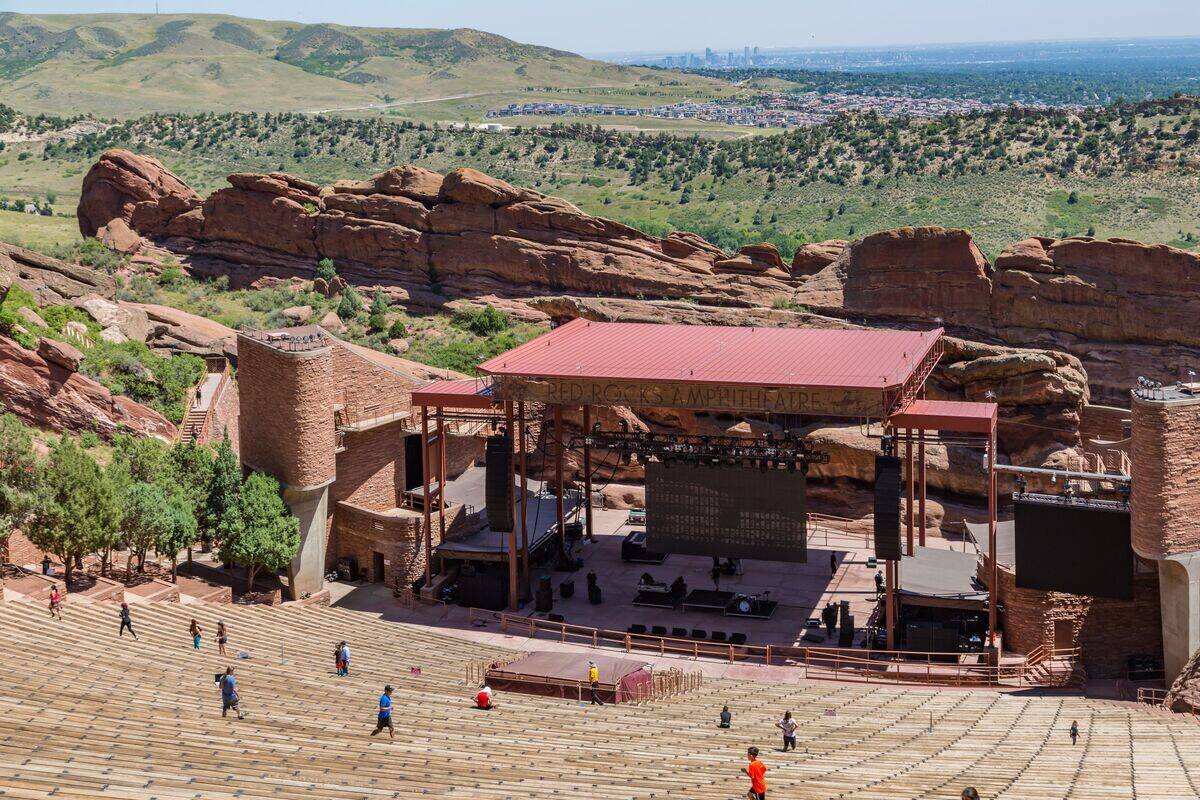 City skyline of Denver, Colorado can be seen on the horizon behind the Red Rocks Amphitheater stage in Morrison, Colorado