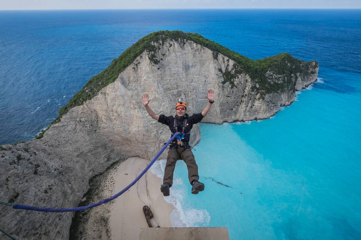 Members of the rope jump french team Pyrenaline jump from atop the rugged rocks overlooking the azure waters, Ionian Islands, Zakynthos, Greece...