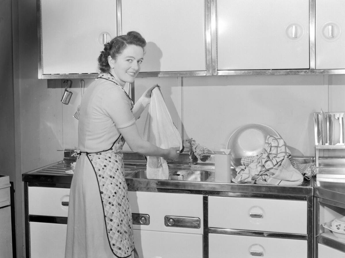 Woman washing cloths in a kitchen sink, 1950.