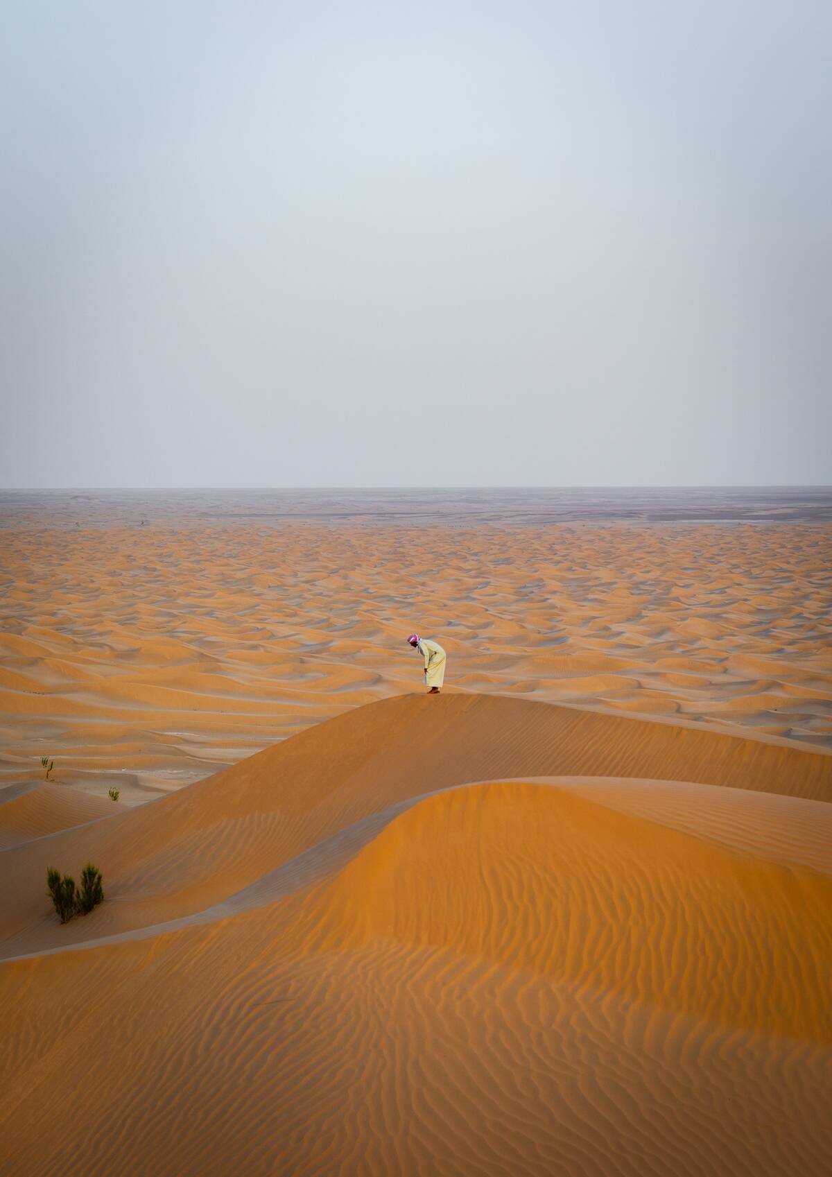 Omani man praying at the top of a dune in rub al khali desert, Dhofar Governorate, Rub al Khali, Oman...