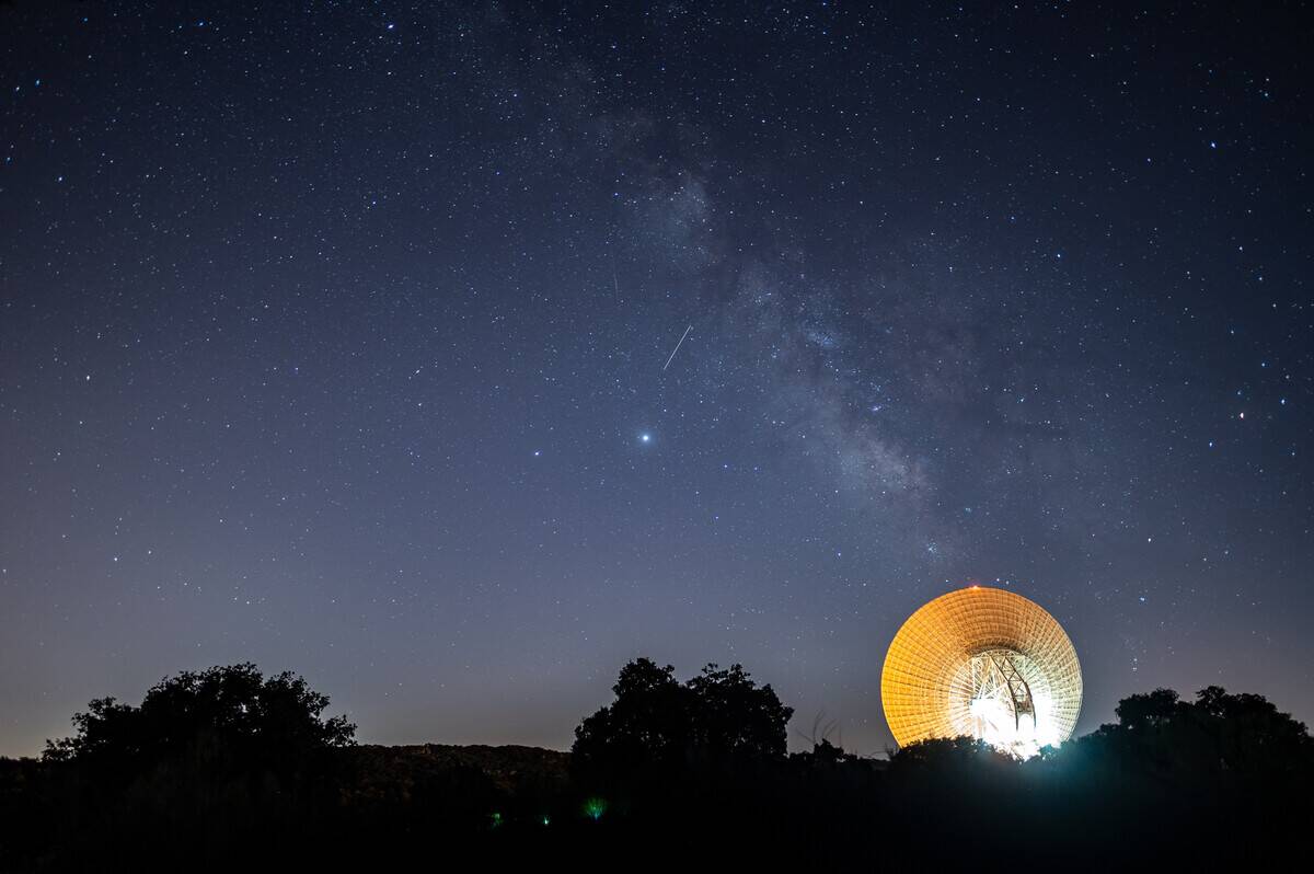 A meteor crossing the night sky over the Milky way and a...