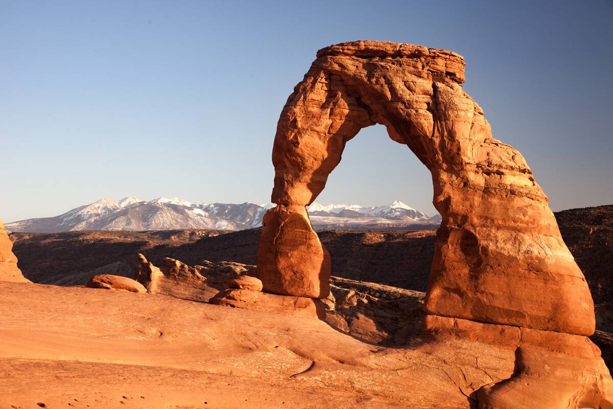 Delicate Arch and Jurassic sandstone of the Entrada Formation, Arches National Park, Utah. La Sal Mountains form the background