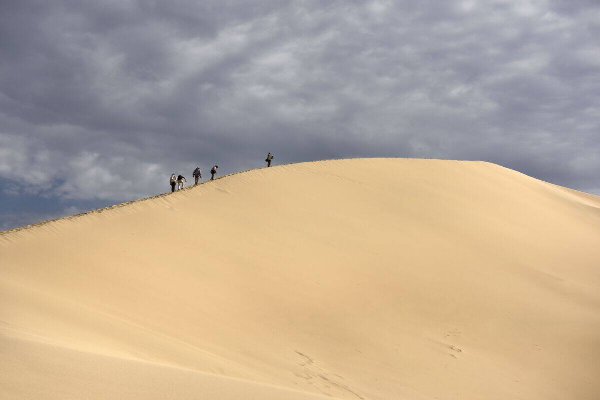 Group of photographers climbing Singing Sand Dune Altyn Emel National Park Kazakhstan