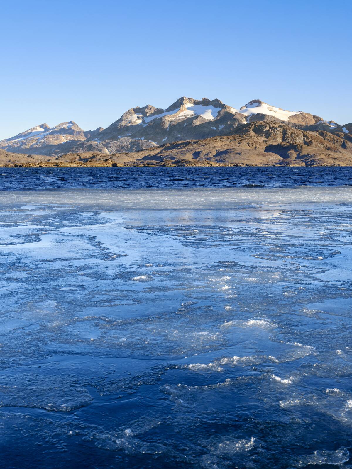 Landscape with thin sea ice in the Ammassaliip Kangertiva Fjord also called Qinngertivaq Fjord. Ammassalik area in East Greenland. North America, Greenland, Danish Territorrry